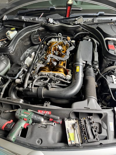 Mercedes log book open on a workbench beside fresh oil, filters and service tools.